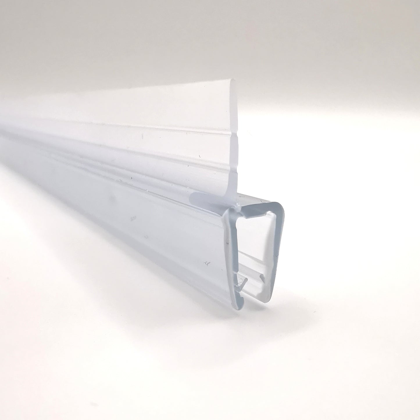 Detailaufnahme eines Ablaufprofils der Marke HÜPPE, transparentes, schmales, längliches, U-förmiges Kunststoffprofil, mit einem Ablaufschutz an der Profilaußenkante, vor weißem Hintergrund