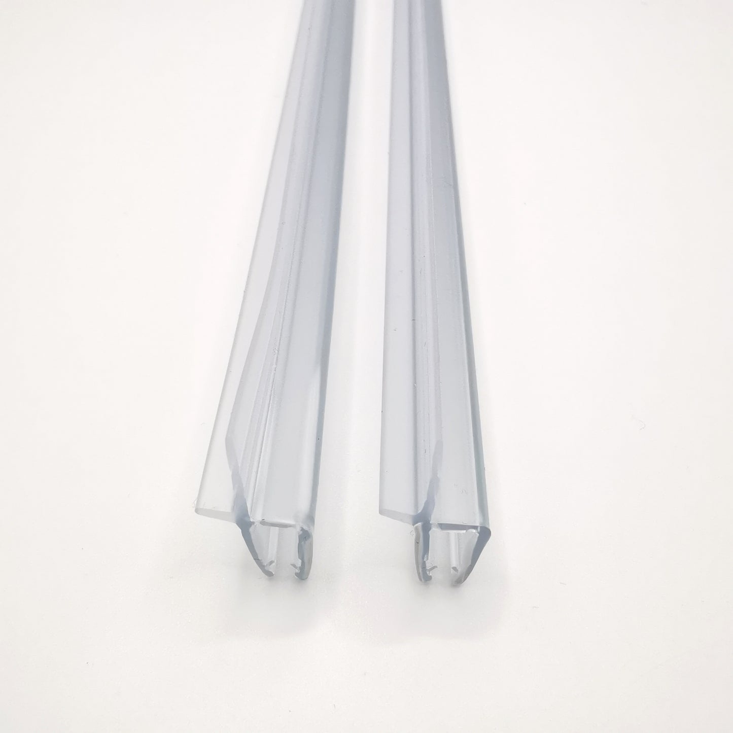 Nahaufnahme zweier Ablaufprofil der Marke HÜPPE, transparente, schmale, längliche, U-förmige Kunststoffprofile, mit einem Ablaufschutz an der Profilaußenkante, vor weißem Hintergrund