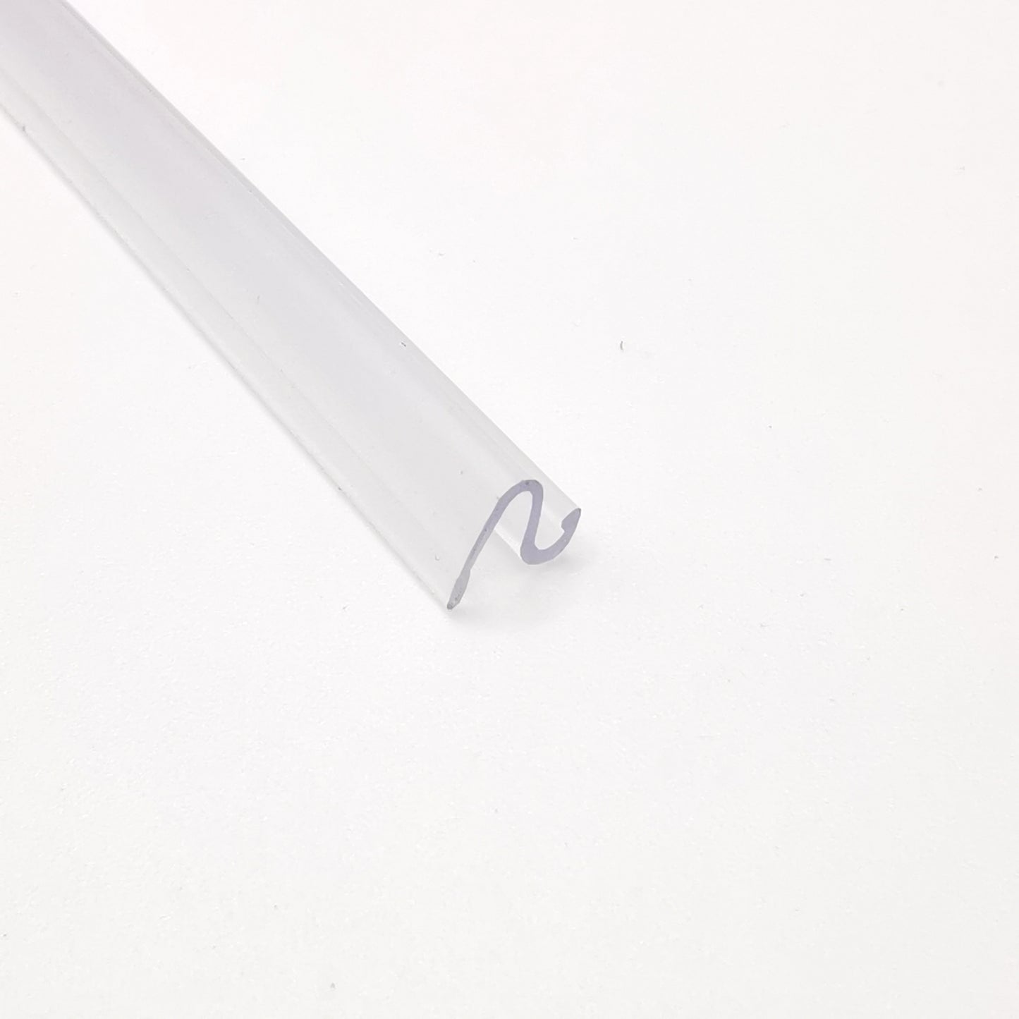 Dichtleiste der Marke HÜPPE, transparentes, schmales, längliches Kunststoffprofil, im Querschnitt S-förmig, vor weißem Hintergrund, Seitenansicht.