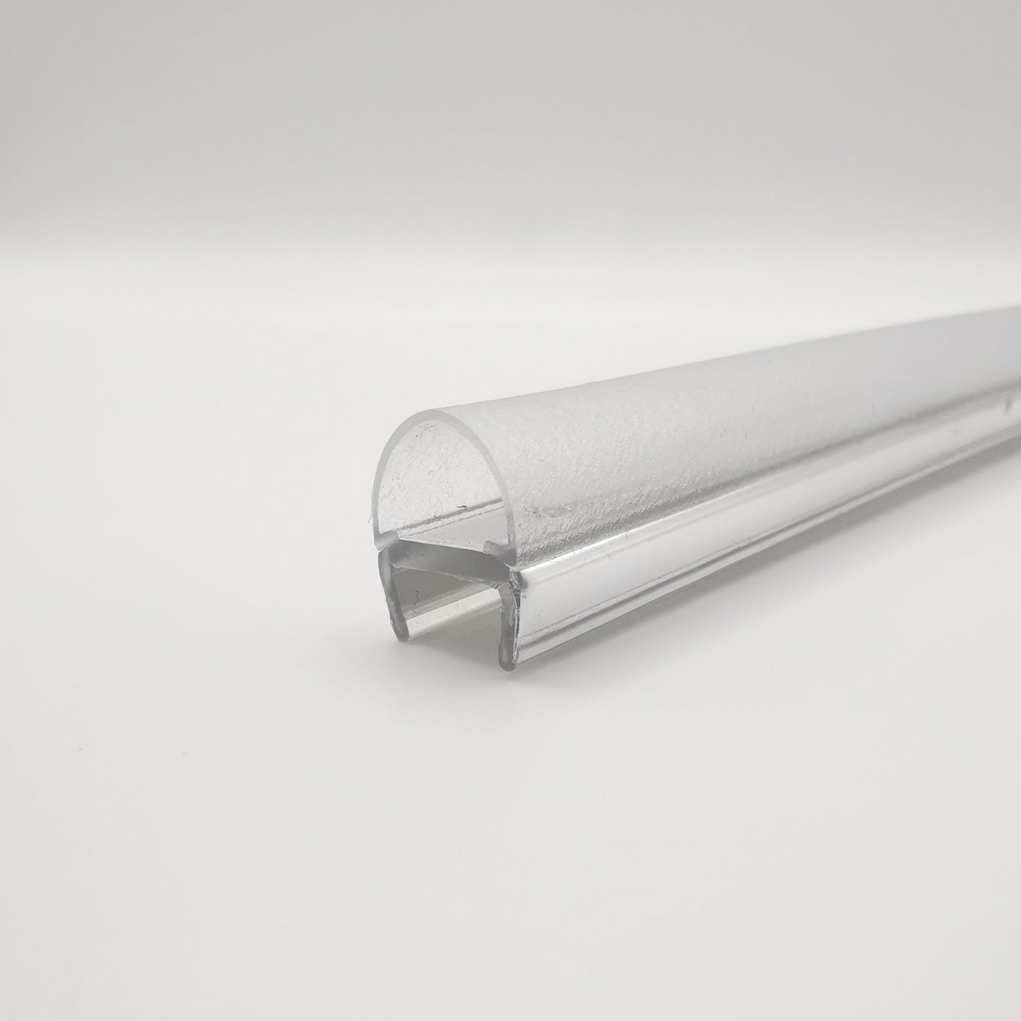 Nahaufnahme eines O-Profils der Marke HÜPPE, silbernes, schmales, längliches, U-förmiges Kunststoffprofil, mit einem transparenten O-förmigen Profil an der Profilvorderseite, vor weißem Hintergrund.