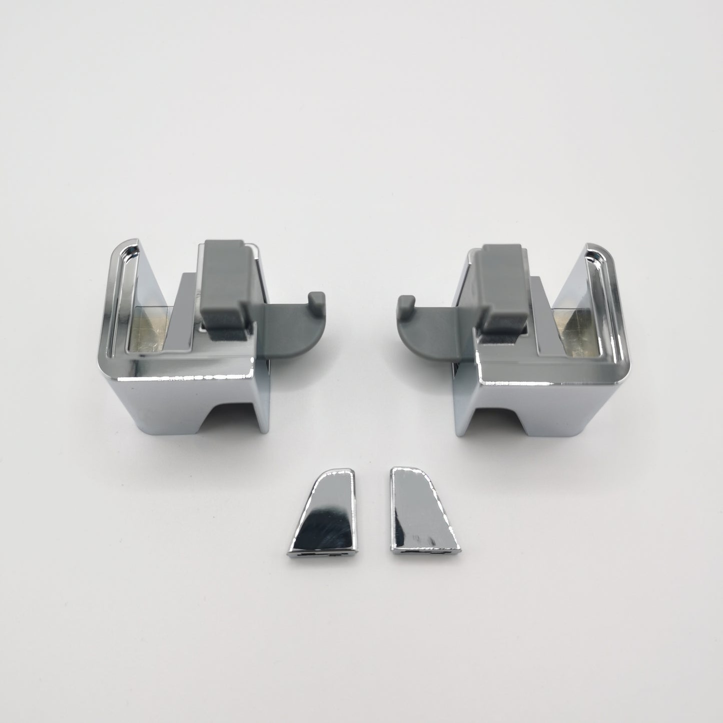 Gleiter-Set der Marke HÜPPE, bestehend aus zwei Silber hochglänzenden, vormontierten, würfelförmigen Gleitern sowie zwei Abdeckkappen, vor weißem Hintergrund, Vogelperspektive.