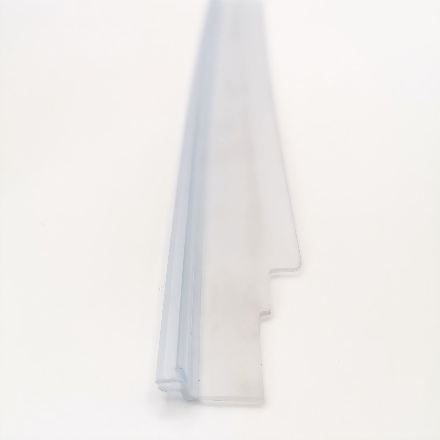 Dichtleiste der Marke HÜPPE, transparentes, schmales, längliches, L-förmiges Kunststoffprofil, mit zwei Lamellen an der linken Profilaußenseite, vor weißem Hintergrund, Vogelperspektive.