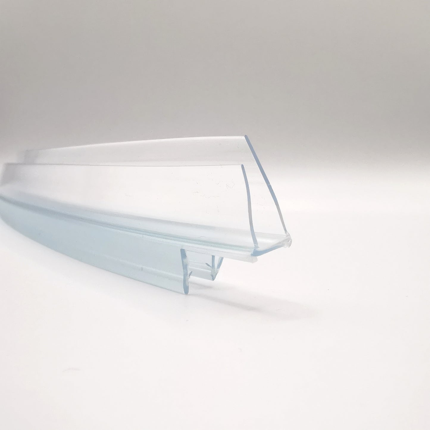 Detailaufnahme eines Ablaufprofils der Marke HÜPPE, transparentes, schmales, längliches, U-förmiges Kunststoffprofil, mit einem Ablaufschutz an den Profilaußenkante, vor weißem Hintergrund