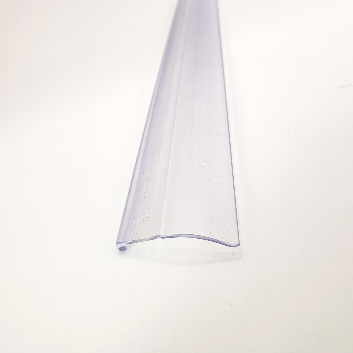 Dichtprofil der Marke HÜPPE, transparentes, flaches, längliches Kunststoffprofil, vor weißem Hintergrund, Vogelperspektive.
