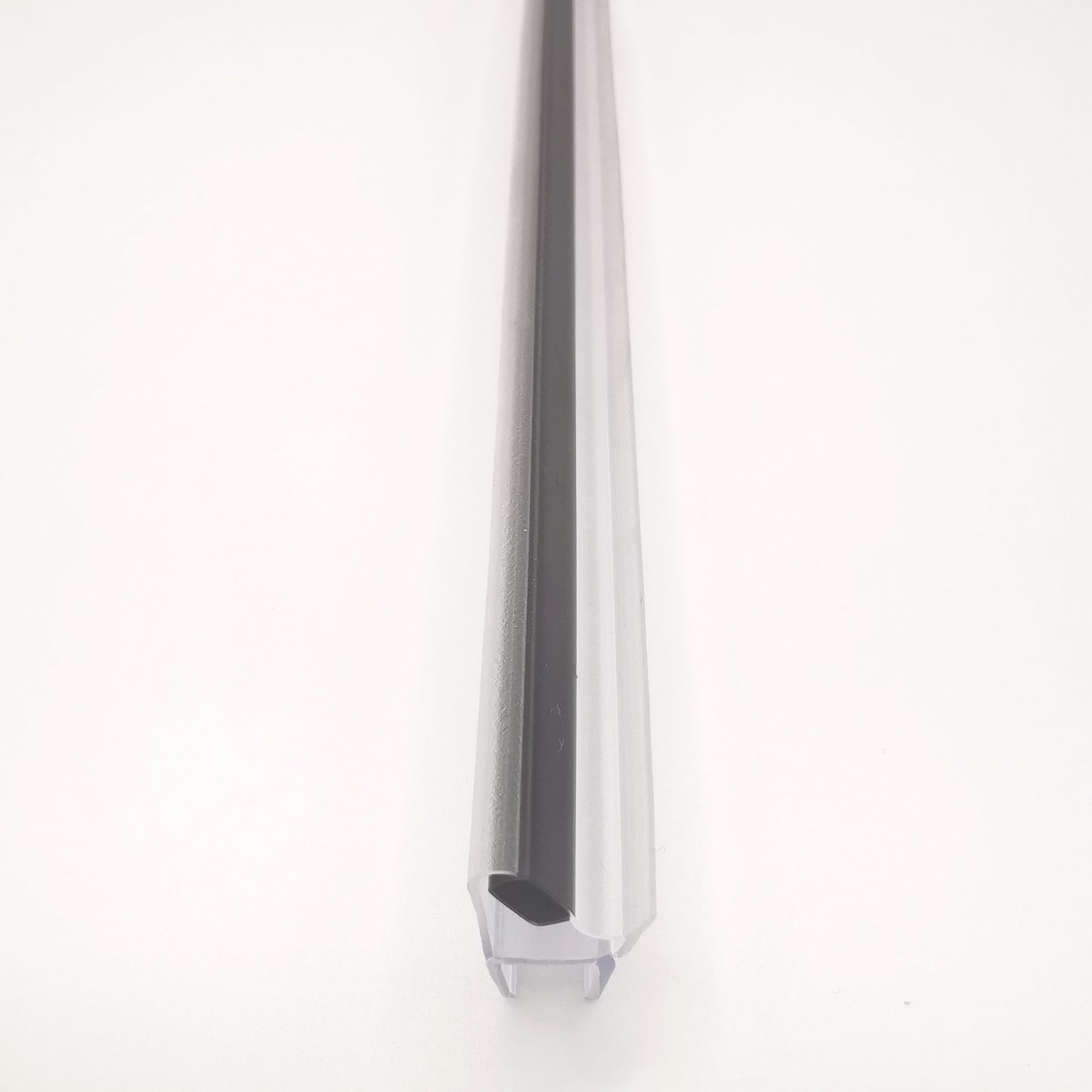 Nahaufnahme einer Magnetleiste der Marke HÜPPE, transparentes, schmales, längliches, U-förmiges Kunststoffprofil, mit einem 45 Grad abgewinkelten Magnetprofil an der Profilvorderseite, vor weißem Hintergrund.