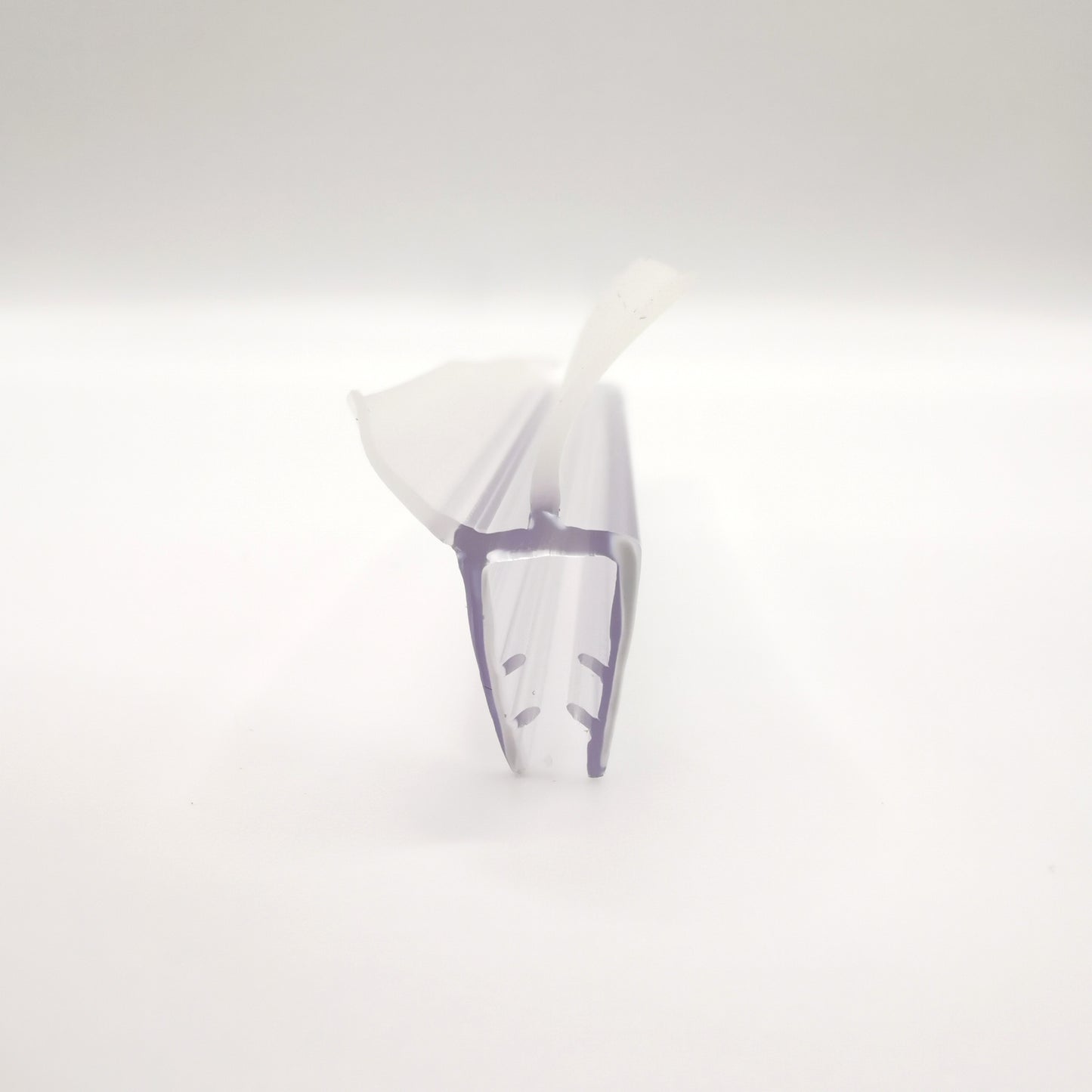 Detailaufnahme eines Ablaufprofils der Marke HÜPPE, transparentes, schmales, längliches, U-förmiges Kunststoffprofil, mit einem Ablaufschutz an der Profilunterseite bzw. Profilaußenkante, vor weißem Hintergrund.