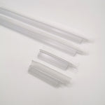 Nahaufnahme Ablaufprofil-Set der Marke HÜPPE, bestehend aus vier transparenten, schmalen, länglichen, U-förmigen Kunststoffprofilen, in zwei Längen, mit einem Ablaufschutz an der Profilunterseite bzw. Profilaußenkante, vor weißem Hintergrund.