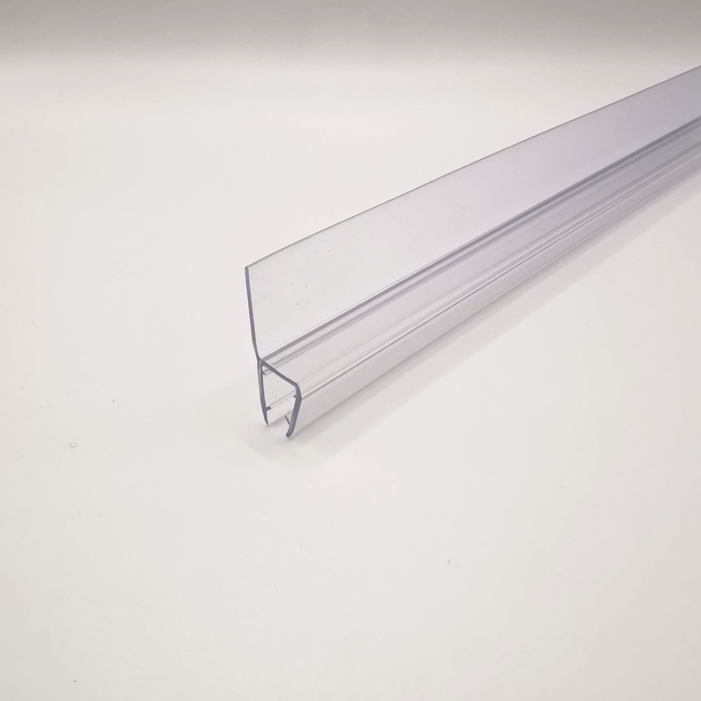 Nahaufnahme einer Dichtleiste der Marke HÜPPE, transparentes, schmales, längliches, U-förmiges, Kunststoffprofil, mit einem Ablaufschutz an der Profilvorderseite, vor hellem Hintergrund, Seitenansicht rechts.