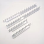 Nahaufnahme Ablaufprofil-Set der Marke HÜPPE, bestehend aus vier transparenten, schmalen, länglichen, U-förmigen Kunststoffprofilen, in zwei Längen, mit einem Ablaufschutz an den Außenkanten der Profilunterseite, vor weißem Hintergrund