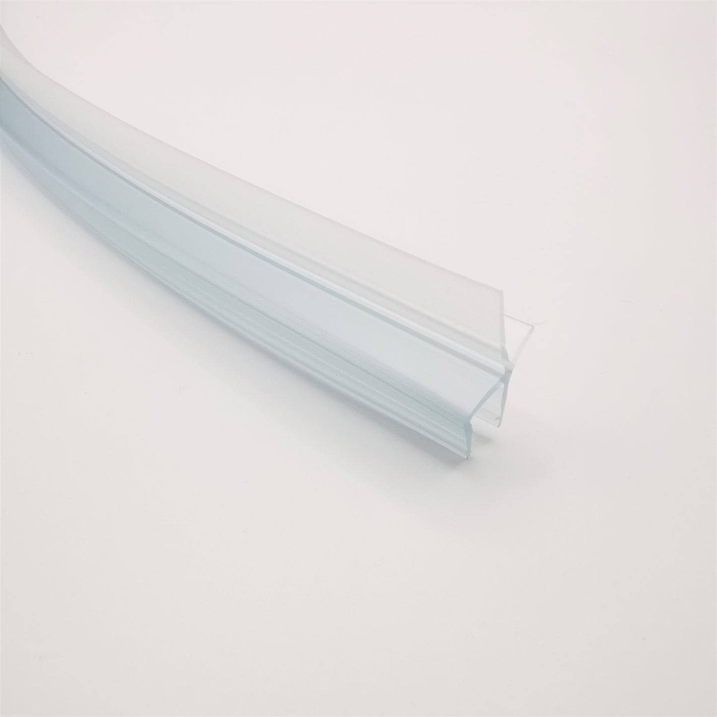 Nahaufnahme einer gebogenen Ablaufleiste der Marke HÜPPE, weißes, schmales, längliches, U-förmiges Kunststoffprofil, mit einem Ablaufschutz an der Profilunterseite, vor weißem Hintergrund.