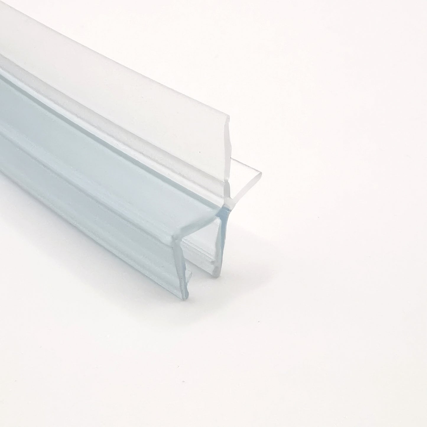 Detailaufnahme einer gebogenen Ablaufleiste der Marke HÜPPE, weißes, schmales, längliches, U-förmiges Kunststoffprofil, mit einem Ablaufschutz an der Profilunterseite, vor weißem Hintergrund.