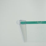 Nahaufnahme eines O-Profils der Marke HÜPPE, montiert an Glasdusche, transparentes, schmales, längliches, U-förmiges Kunststoffprofil, mit einem O-förmigen Profil an der Profilvorderseite, vor weißem Hintergrund.