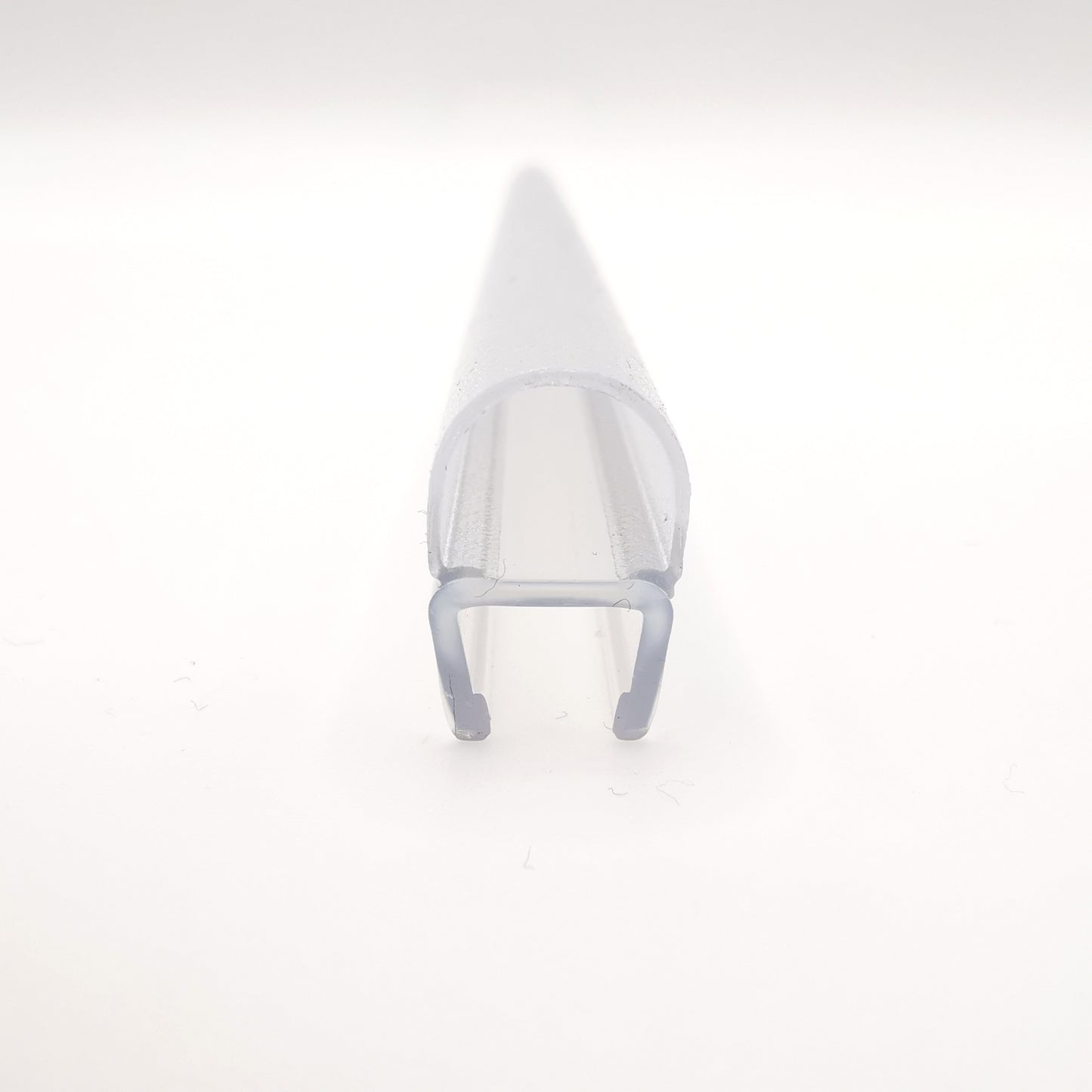 Detailaufnahme eines O-Profils der Marke HÜPPE, transparentes, schmales, längliches, U-förmiges Kunststoffprofil, mit einem O-förmigen Profil an der Profilvorderseite, vor weißem Hintergrund.