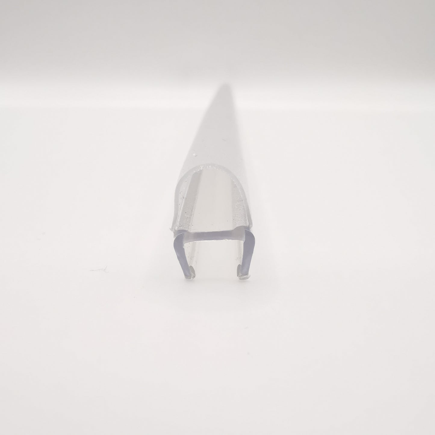 Detailaufnahme eines O-Profils der Marke HÜPPE, transparentes, schmales, längliches, U-förmiges Kunststoffprofil, mit einem O-förmigen Profil an der Profilvorderseite, vor weißem Hintergrund.