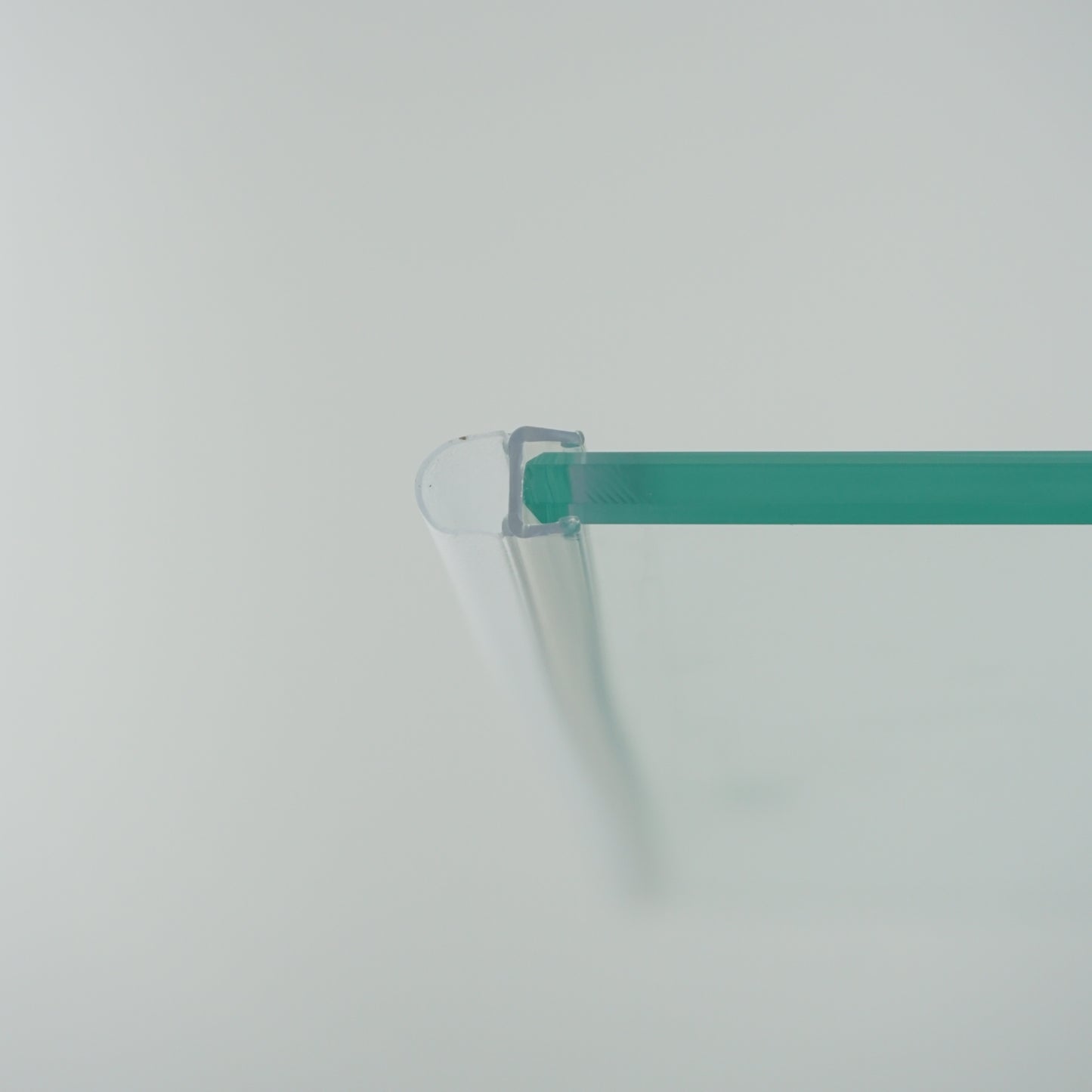 Nahaufnahme eines O-Profils der Marke HÜPPE, montiert an Glasdusche, transparentes, schmales, längliches, U-förmiges Kunststoffprofil, mit einem O-förmigen Profil an der Profilvorderseite, vor weißem Hintergrund.