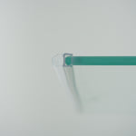 Nahaufnahme eines O-Profils der Marke HÜPPE, transparentes, schmales, längliches, U-förmiges Kunststoffprofil, mit einem O-förmigen Profil an der Profilvorderseite, montiert an der rechten Außenseite einer Glasdusche, vor weißem Hintergrund.