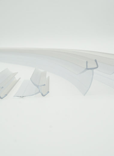 Ablaufprofil-Set der Marke HÜPPE bestehend aus vier gebogenen, transparenten, schmalen, länglichen, U-förmigen Kunststoffprofil, mit einem Ablaufschutz an der Profilunterseite, in zwei Längen, vor weißem Hintergrund.