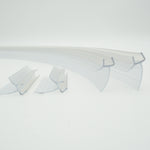 Ablaufprofil-Set der Marke HÜPPE bestehend aus vier gebogenen, transparenten, schmalen, länglichen, U-förmigen Kunststoffprofil, mit einem Ablaufschutz an der Profilunterseite, in zwei Längen, vor weißem Hintergrund.