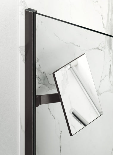 Select+ Mirror, Schwarzer, matter, quadratischer Spiegel der Marke HÜPPE, befestigt an einer Wandleiste einer Glasdusche, vor einer hellen, strukturierten Wand.