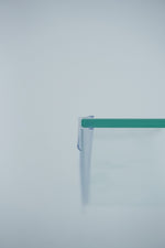 Nahaufnahme einer Dichtleiste der Marke HÜPPE, transparentes, schmales, längliches, U-förmiges, Kunststoffprofil, mit einem Ablaufschutz an der Profilvorderseite, montiert an Glasdusche, vor hellem Hintergrund, Seitenansicht rechts.