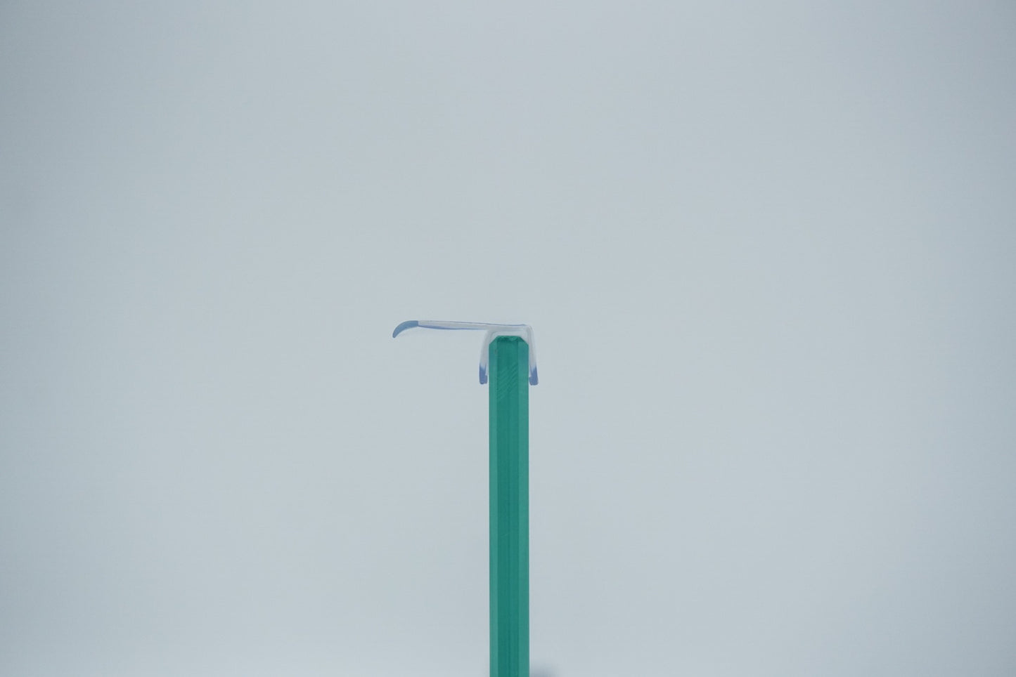 Nahaufnahme einer Dichtleiste der Marke HÜPPE, transparentes, schmales, längliches, U-förmiges, Kunststoffprofil, mit einem Ablaufschutz an der Profilvorderseite, montiert an Glasdusche, vor hellem Hintergrund, Frontansicht.