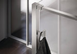Select+ Hook, silberner Haken der Marke HÜPPE, der an einem senkrechten Profil einer Glasdusche montiert ist, daran hängt ein graues Handtuch, in einem modernen Badezimmer mit dunkelbraunem Fußboden.