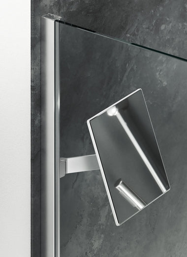 Select+ Mirror, Silberner, quadratischer Spiegel der Marke HÜPPE, befestigt an einer Wandleiste einer Glasdusche, vor einer dunklen, strukturierten Wand.