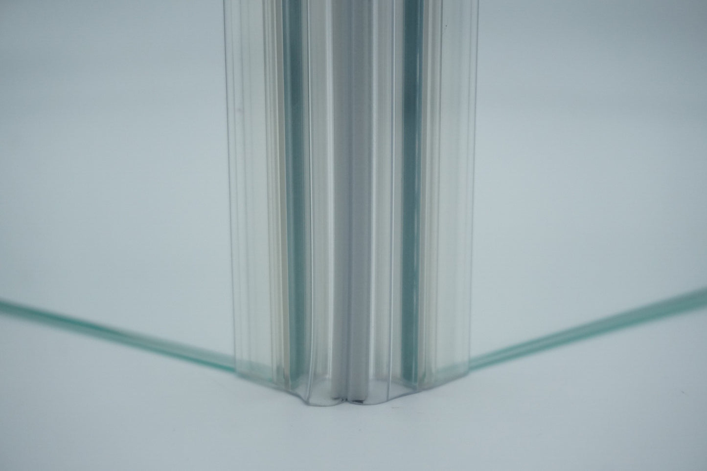 Nahaufnahme, von zwei Magnetleisten der Marke HÜPPE, montiert an Glasdusche, transparente, schmale, längliche, U-förmige Kunststoffprofile, mit Magnetprofilen, an der Vorderseite, 45 Grad angewinkelt, Magneten bilden zusammen geschlossenen 90 Grad Winkel, vor weißem Hintergrund, Frontansicht.