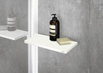 Select+ Wiper, Weiße, matte Ablage der Marke HÜPPE befestigt an einer Wandleiste einer Glasdusche, darauf steht ein Seifenspender und eine Handseife, vor einer hellgrauen strukturierten Wand.
