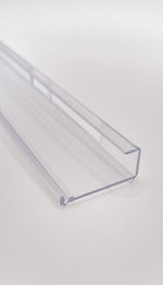 Nahaufnahme einer Glasklemmleiste der Marke HÜPPE, transparentes, schmales, längliches, Kunststoffprofil, mit einem L-förmigen Querschnitt, vor weißem Hintergrund, Seitenansicht.
