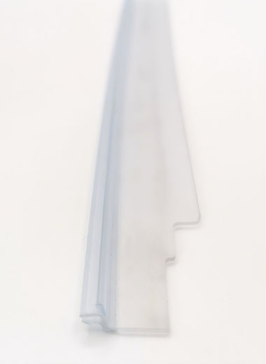Dichtleiste der Marke HÜPPE, transparentes, schmales, längliches, L-förmiges Kunststoffprofil, mit zwie Lamellen an der linken Profilaußenseite, vor weißem Hintergrund, Vogelperspektive.
