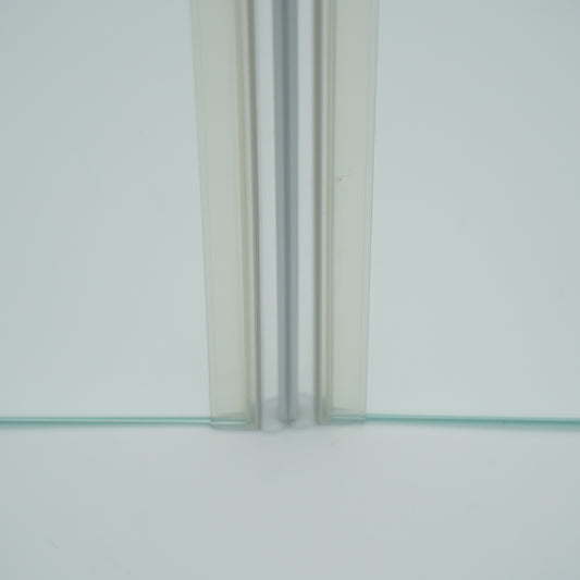 Nahaufnahme von zwei Magnetleisten der Marke HÜPPE, montiert an Glasdusche, transparente, schmale, längliche, U-förmige Kunststoffprofile, mit Magnetprofilen an der Vorderseite, Magneten bilden zusammen geschlossenen 180 Grad Winkel, vor weißem Hintergrund, Frontansicht.
