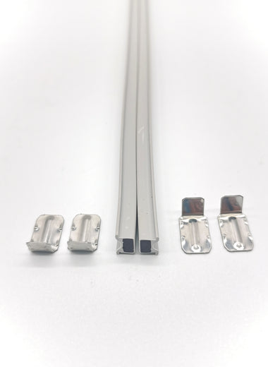 Zwei Stück Magnetband der Marke HÜPPE, hellgraue, schmale, längliche, rechteckige, parallel haftende Magnetprofile, sowie vier kleine Metallwinkel, vor weißem Hintergrund, Vogelperspektive.

