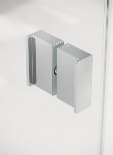 Nahaufnahme einer Duschkabine mit einem Silber hochglänzenden, rechteckigen, minimalistischen, HÜPPE Komfortgriff im Fokus, vor einem hellen Hintergrund.