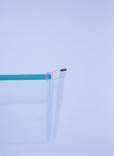 Nahaufnahme einer Magnetleiste der Marke HÜPPE, transparentes, schmales, längliches, U-förmiges Kunststoffprofil, mit einer Magnetleiste an der Profilvorderseite, vor weißem Hintergrund, montiert an Glasdusche, Seitenansicht links.
