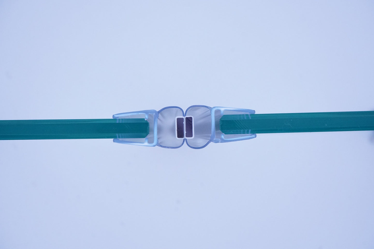 Nahaufnahme, Ansicht von oben, von zwei Magnetleisten der Marke HÜPPE, montiert an Glasdusche, transparente, schmale, längliche, U-förmige Kunststoffprofile, mit Magnetprofilen an der Vorderseite, Magneten bilden zusammen geschlossenen 180 Grad Winkel, vor weißem Hintergrund, Vogelperspektive.
