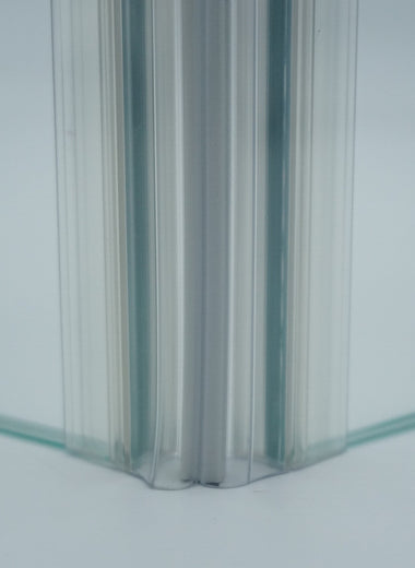 Nahaufnahme, von zwei Magnetleisten der Marke HÜPPE, montiert an Glasdusche, transparente, schmale, längliche, U-förmige Kunststoffprofile, mit Magnetprofilen, an der Vorderseite, 45 Grad angewinkelt, Magneten bilden zusammen geschlossenen 90 Grad Winkel, vor weißem Hintergrund, Frontansicht.
